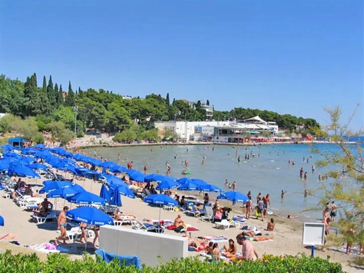 Locals playing picigin in shallow water at a busy sandy beach